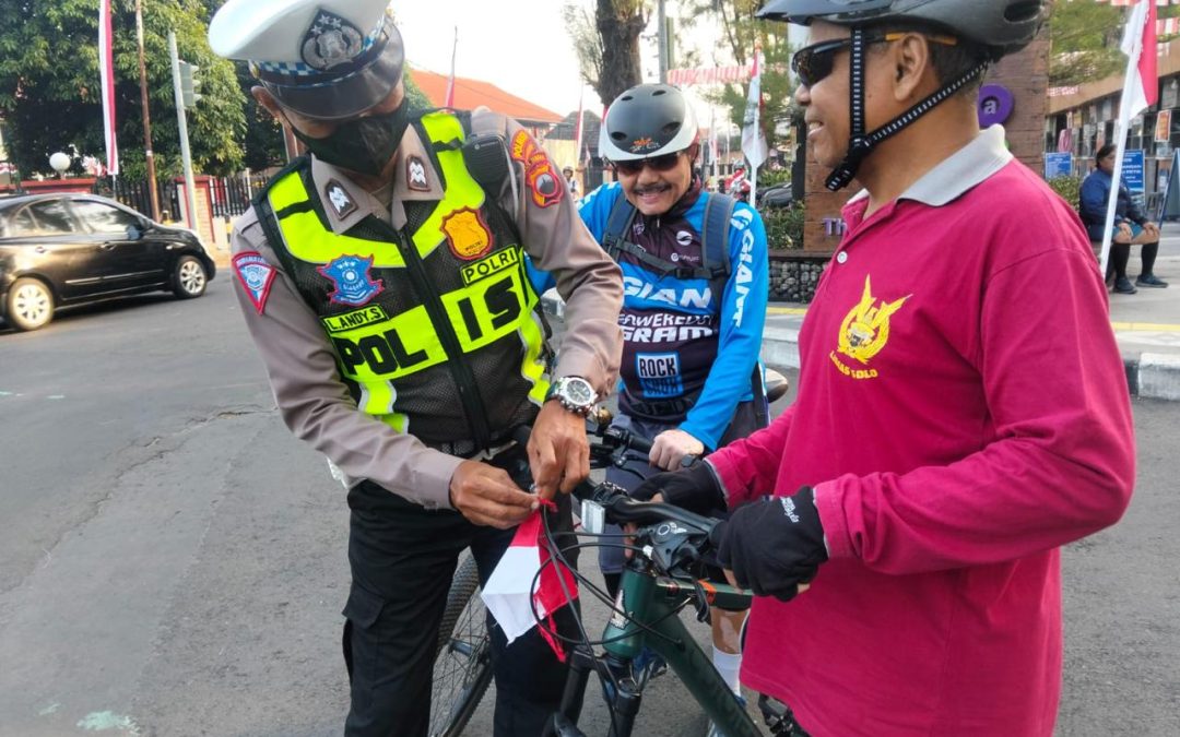 Personel Sat Lantas Polresta Surakarta Bagikan Bendera Merah Putih kepada Pesepeda