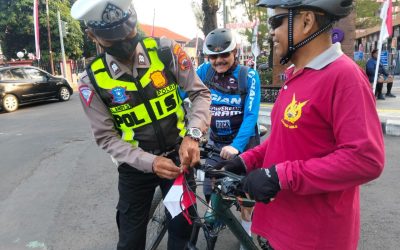 Personel Sat Lantas Polresta Surakarta Bagikan Bendera Merah Putih kepada Pesepeda